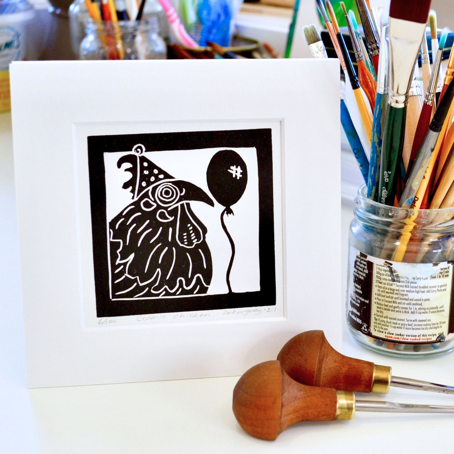 Lino print hand printed by Helen Gray. Cosmic Chicken- rooster with party hat and balloon.