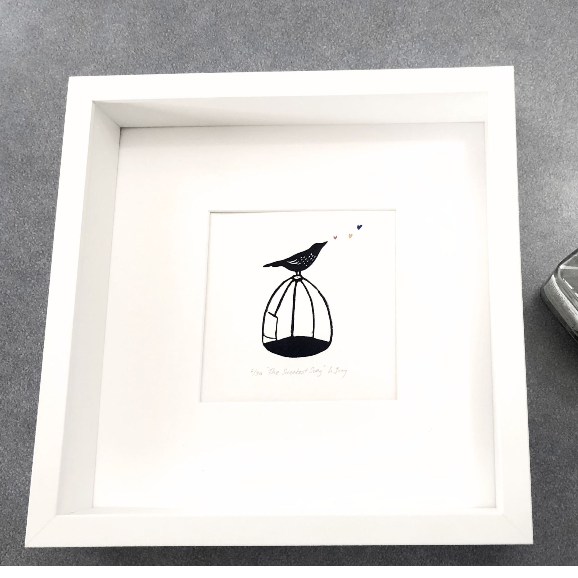 Lino print with watercolour, The Sweetest Song, a bird singing on a cage, original artwork by Helen Gray