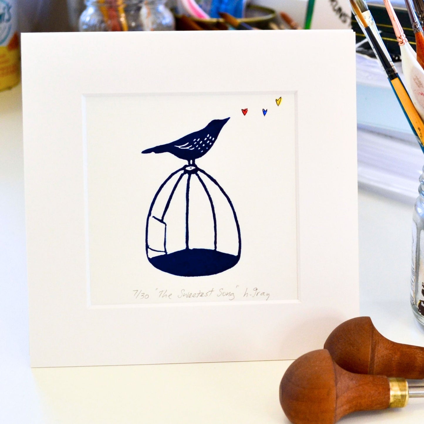 Lino print with watercolour, The Sweetest Song, a bird singing on a cage, original artwork by Helen Gray