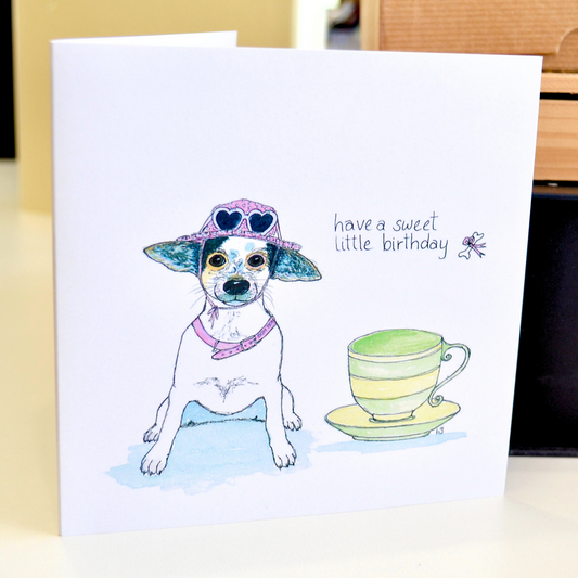 A chihuahua with a pink sunhat, pink collar and loveheart sunglasses with a green teacup. The title reads "Have a sweet little birthday".