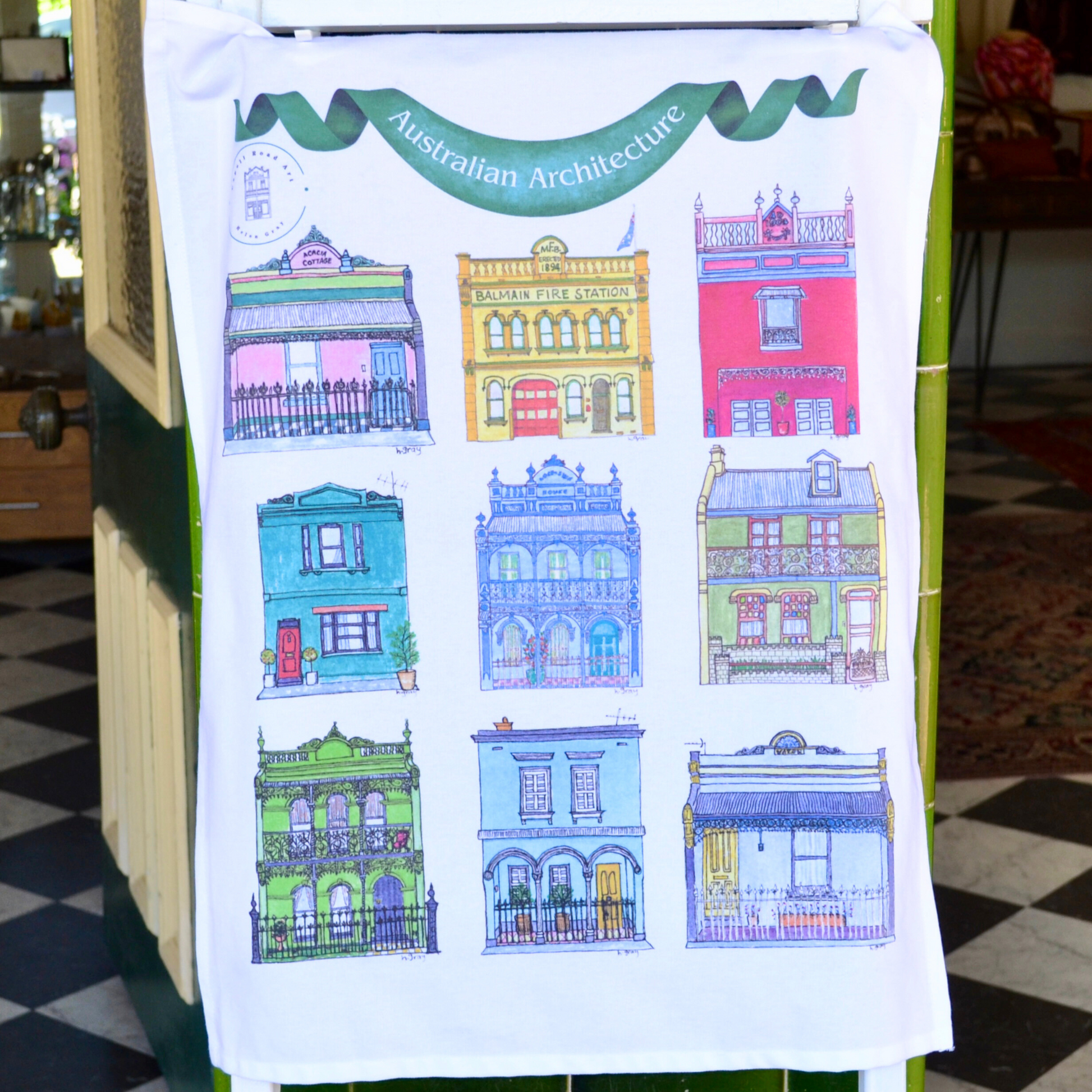 A white tea towel with 9 beautiful, colourful Australian buildings from an original watercolour by Helen Gray. Printed on a white background on 100%soft cotton, with a green banner that says Australian Architecture.